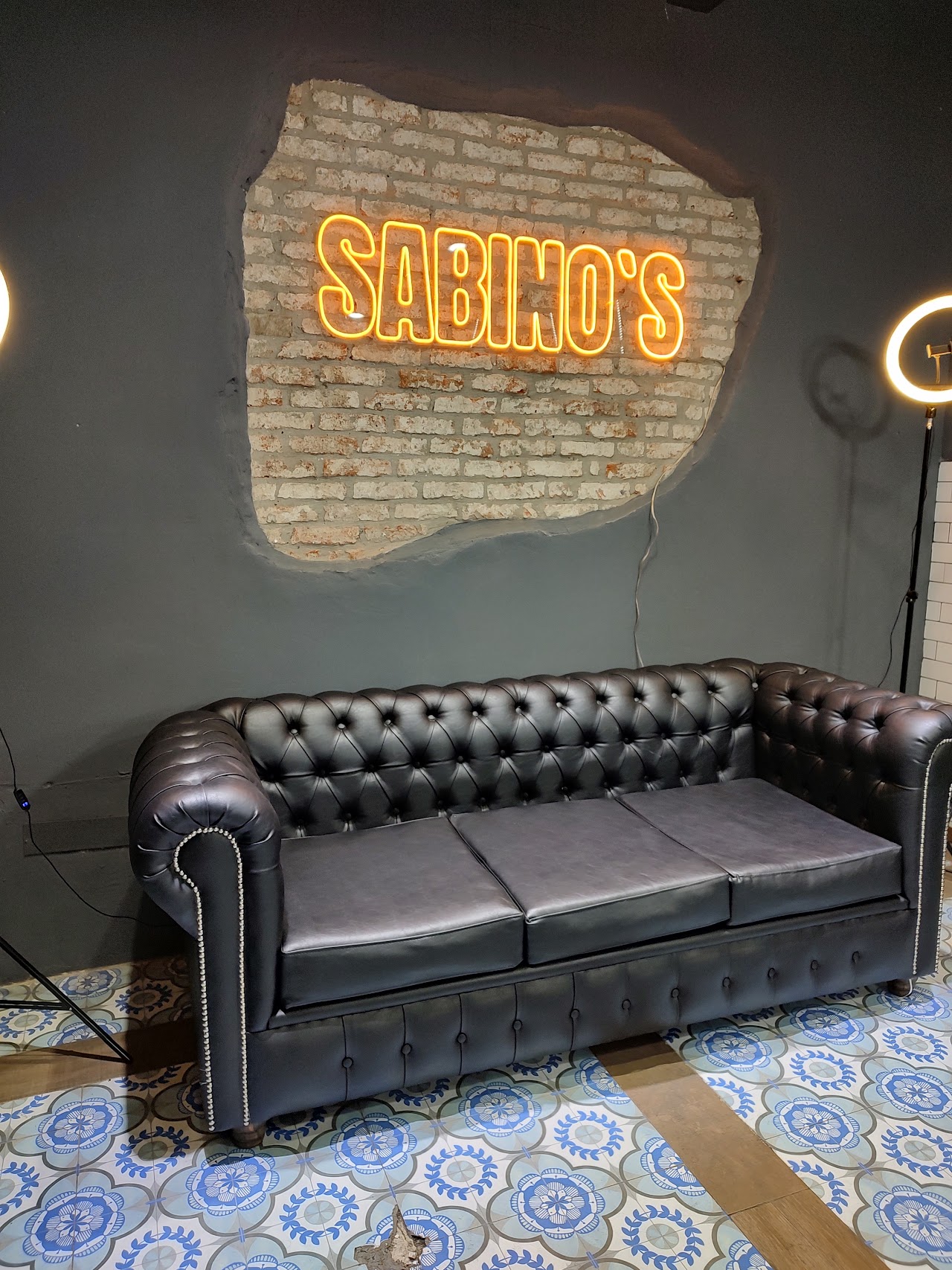 Cartel de neón Sabino's sobre sillón de cuero en la barbería